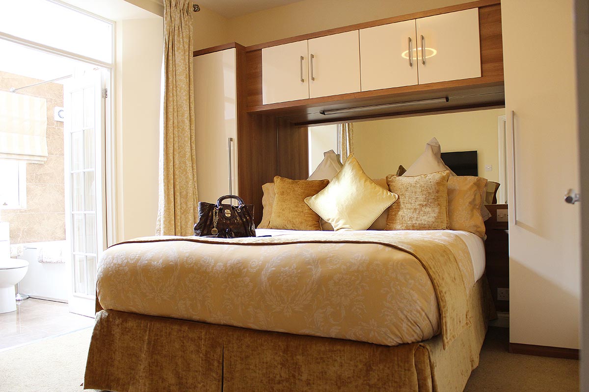 The bedroom in one of our 2 bedroom extended stay apartments leading to an en-suite bathroom